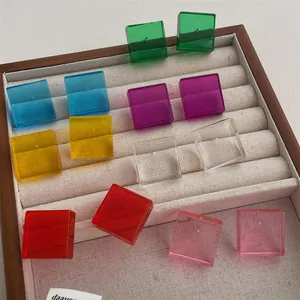 Macro shot of colorful transparent acrylic cube stud earrings displayed in a velvet box