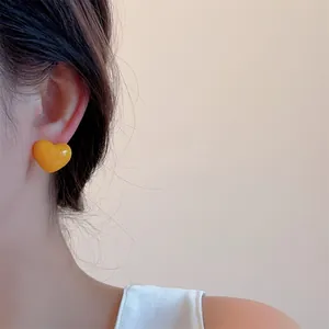 Close-up of bright yellow heart stud earring on model for sweet minimalist style
