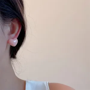 Close-up of sweet pastel pink heart stud earring on model's ear for spring style