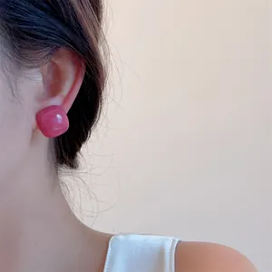 Close-up of bright pink rectangular resin stud earrings showing smooth glazed finish