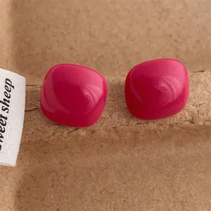 Close-up of bright pink candy-colored square heart studs on a textured brown base