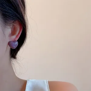 Close-up of taro purple heart-shaped earring worn on ear with a glossy resin finish