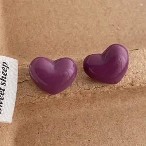 Detailed macro view of purple heart-shaped stud earrings on a textured paper background