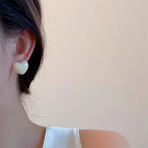 Close-up of sweet cream white heart stud earrings on model for a minimalist look