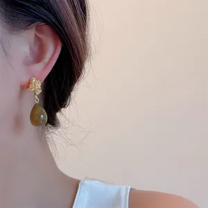 Olive green water drop earrings with wrinkled gold metal detail on model