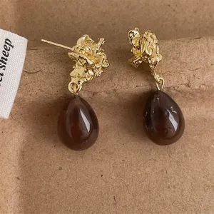 Detail of vintage gold textured metal earrings with amber resin waterdrop pendants