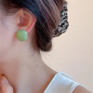 Close-up of a model wearing minimalist light green square resin earrings with soft rounded corners