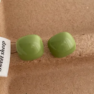 Close-up of avocado green square stud earrings with smooth glossy enamel finish