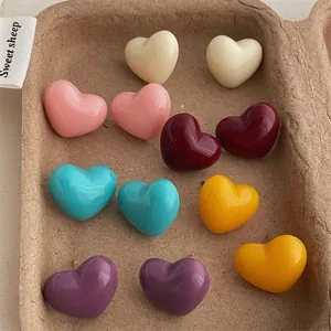Colorful heart-shaped stud earrings set in various pastel colors on a rustic tray