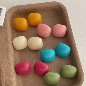 Set of colorful square stud earrings in candy colors on a textured paper tray