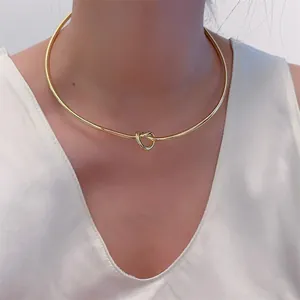 Nahaufnahme eines eleganten goldenen Knotenchokers aus Metall auf weißem Seidenhemd