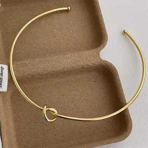Detail einer goldenen Knotenhalskette mit Kugelenden in einer rustikalen Geschenkbox