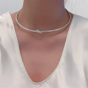 Minimalistisches silberfarbenes starres Choker-Halsband mit poliertem Metallknoten am Modell