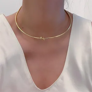 Minimalistischer goldener Knoten-Choker aus Edelstahl auf weißem Seidenoutfit