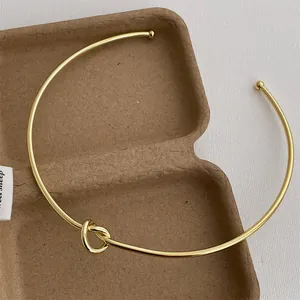 Detail eines minimalistischen Gold-Chokers mit Knotendesign und polierten Kugelenden