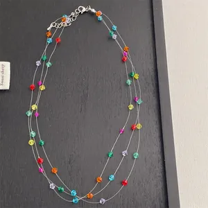 Detalle de un collar de tres capas con cuentas facetadas de colores y cierre de mosquetón