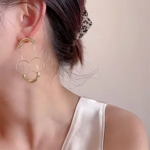 Eleganti orecchini geometrici con nappe dorate indossati da una modella di profilo
