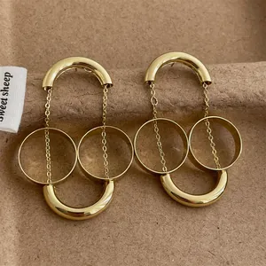 Vista macro di orecchini minimalisti in oro a doppio anello su espositore marrone