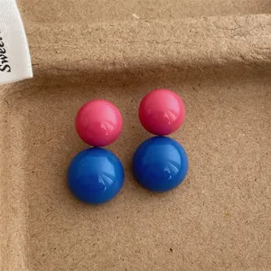 Dettaglio macro di eleganti orecchini a sfera bicolore in rosa vivace e blu brillante