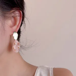 Dettaglio dell'orecchino in resina rosa con scaglie di conchiglia e foglia oro