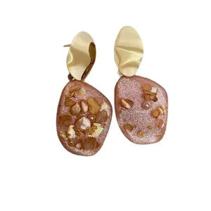 Orecchini irregolari in metallo dorato con ciondolo in resina rosa, conchiglie e foglia d'oro