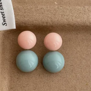 Dettaglio macro di orecchini a sfera rosa e blu su uno sfondo marrone con trama calda