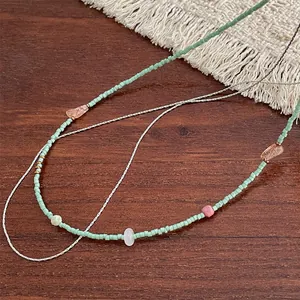 Détail du collier de perles vert menthe avec pierres minérales sur tapis à franges