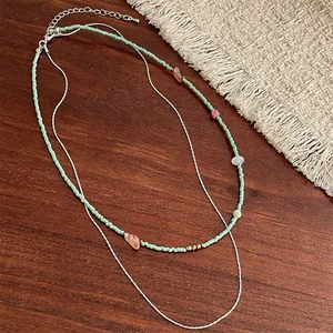 Collier double rangée en perles vert menthe et pierres naturelles sur bois foncé