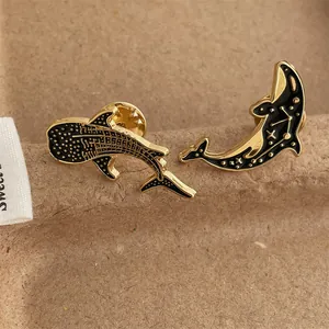 Detail of whale and whale shark enamel pins with starry sky pattern on craft paper