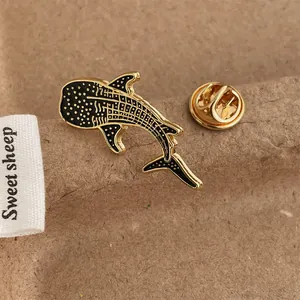 Macro view of whale shark enamel brooch with gold spots on a textured brown background