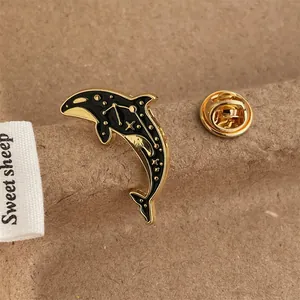Macro shot of an orca whale enamel pin featuring a black and gold starry sky design