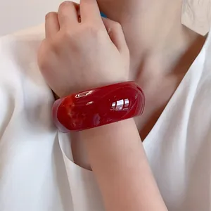 Irregular wide red resin bangle bracelet with translucent finish and minimalist design