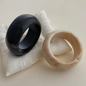 Irregular resin bangle set with solid black and marble patterns in a wide geometric design