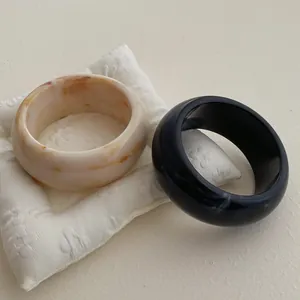 Detail of chunky resin bangles with marbled texture and high-gloss black finish