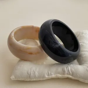 Irregular resin bangle bracelets with marble patterns in black and cream cream colors