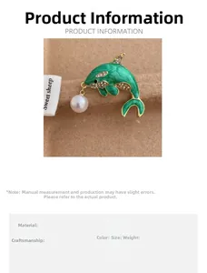 Close-up of green enamel dolphin brooch with white pearl pendant and rhinestones