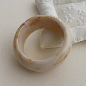 Macro detail of wide resin bangle showing vintage cream amber marble texture and smooth edges