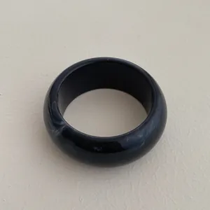 Detail view of a wide black resin bangle with white marble texture and smooth finish
