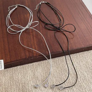 Collares con lazo de cordón largo y colgantes de rosa plateada sobre fondo de madera oscura