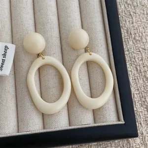 Detailed macro view of creamy white resin drop earrings with a smooth polished finish