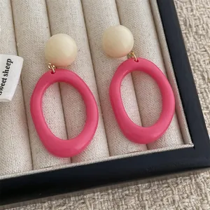 Retro resin hoop earrings with cream stud and pink circle on a fabric display tray