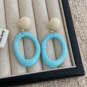 Macro detail of vintage resin earrings with beige beads and sky blue oval hoops