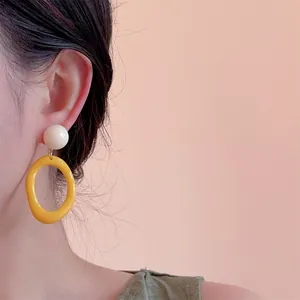 Close-up of retro color-block resin hoop earrings with white beads on a female model
