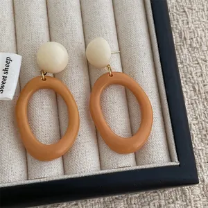 Detail of vintage resin hoop earrings in caramel and cream on a beige velvet tray