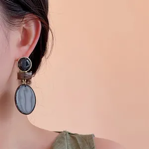 Close-up of geometric resin drop earrings with marble texture on model side profile