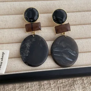 Geometric resin drop earrings with marble pattern and gold-plated accents on velvet