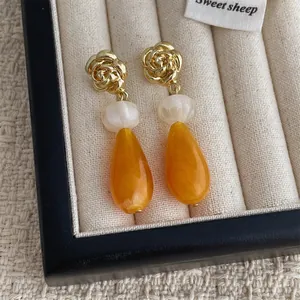 Détails de boucles d'oreilles rose avec perles crème et gouttes en résine orange