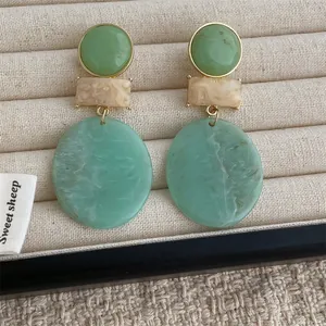 Detailed macro view of geometric resin earrings with green and beige marble patterns