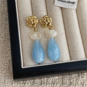 Détail de boucles d'oreilles rose doré vintage et gouttes bleues dans un écrin en velours