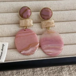 Detail of candy-colored resin geometric earrings with marble texture on jewelry box